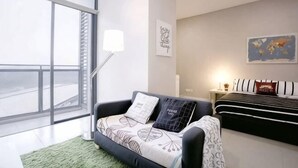 Un salon moderne avec un canapé, un lit, une lampe sur pied et une grande fenêtre.
