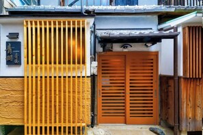 A traditional Japanese entrance with a wooden gate, a sliding door, and a small step leading to the entrance. - AOU･SEITOKKU (Osaka)