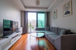A modern living room with a flat-screen TV, a sofa, a coffee table, and a view through large windows. - Ofton Elysium Soul Residence (Istanbul)