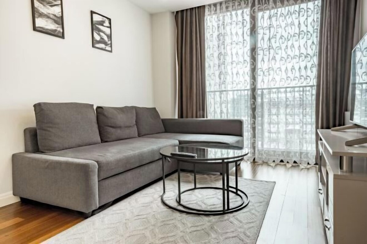A modern living room with a grey sofa, a round coffee table, and a patterned rug.
