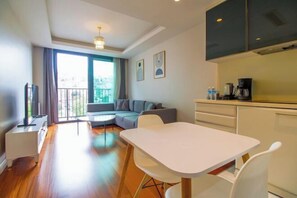 A modern living room with a sofa, a dining table, and a kitchen area with cabinets and a coffee machine. - Ofton Elysium Soul Residence (Istanbul)