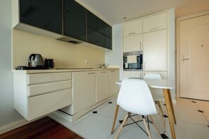A compact kitchen with white cabinetry, a white chair, and a small dining table. - Ofton Elysium Soul Residence (Istanbul)