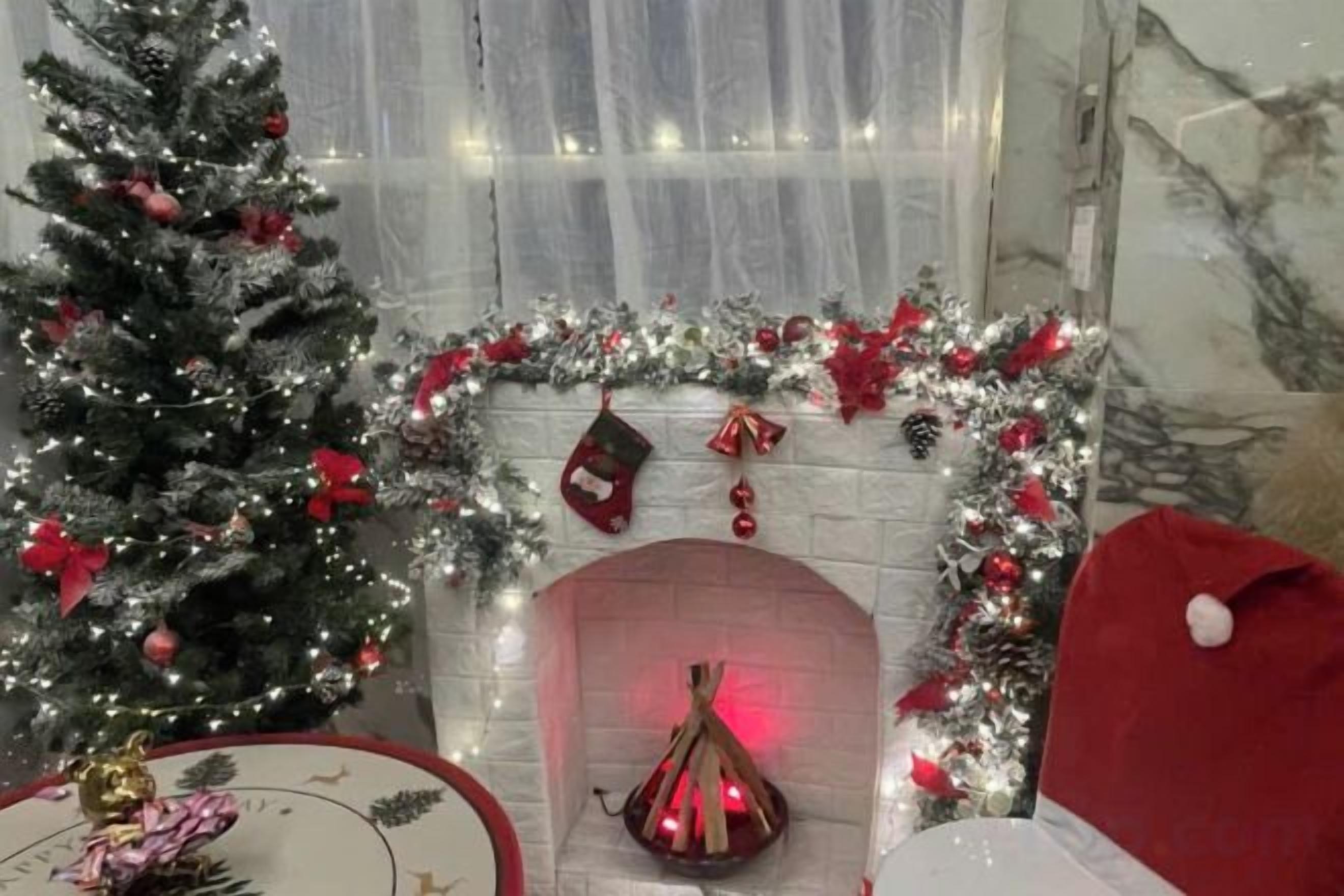 A room with a fireplace, a Christmas tree, and festive decorations.