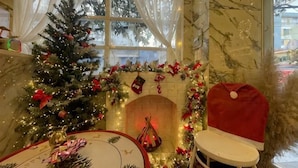 A Christmas-themed room with a fireplace, a Christmas tree, and festive decorations. - A In Hotel Atistar (Ho Chi Minh City)
