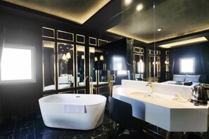 Une salle de bain moderne avec une baignoire sur pieds, un grand meuble-lavabo avec un miroir et une fenêtre laissant entrer la lumière naturelle.
