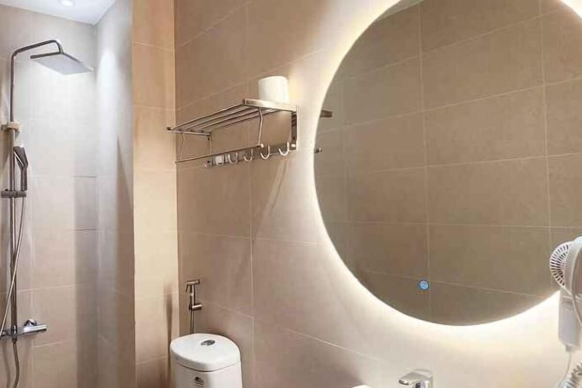 A modern bathroom with a large mirror, a shower, and a toilet.