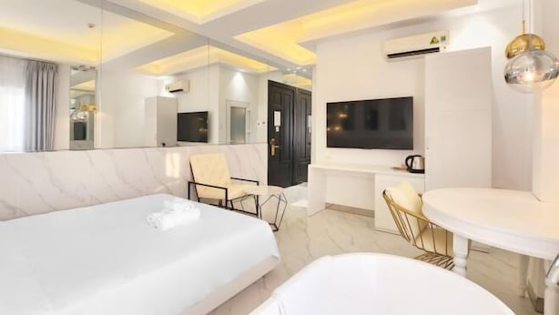 A modern hotel room with a large bed, a seating area, a TV, and a dining table. - A In Hotel Atistar (Ho Chi Minh City)