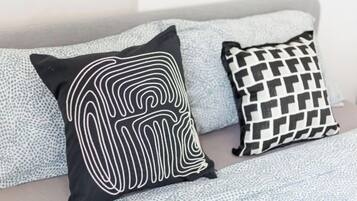 A bed with a grey headboard and two pillows with distinct patterns.