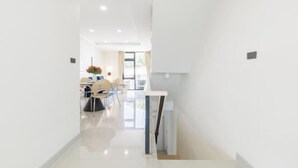 A modern, well-lit hallway leading to a dining area with a table and chairs. - Bangkok Four-Bedroom Single Family Villa [near Sangtai Shopping Center + Royal Park] (Bangkok)