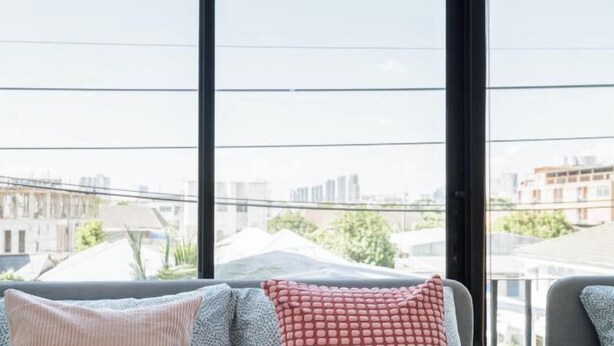 A room with a large window, two grey chairs, and a red pillow. - Bangkok Four-Bedroom Single Family Villa [near Sangtai Shopping Center + Royal Park] (Bangkok)