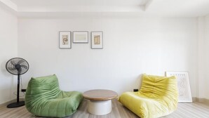 A room with a green and yellow bean bag chairs, a small round table, and a fan. There are three framed pictures on the wall. - Bangkok Four-Bedroom Single Family Villa [near Sangtai Shopping Center + Royal Park] (Bangkok)
