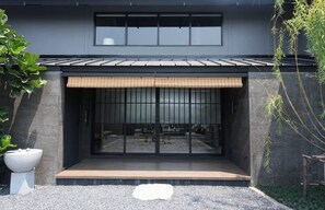 A modern building with a dark facade, large windows, and a wooden deck. - Ojisan House (Chon Buri)