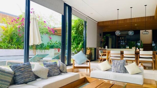 A modern living room with a sofa, coffee table, and dining area. - Joy Villa Phu Quoc (Phu Quoc Island)