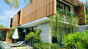 A modern house with a swimming pool, wooden deck, and lush greenery. - Joy Villa Phu Quoc (Phu Quoc Island)
