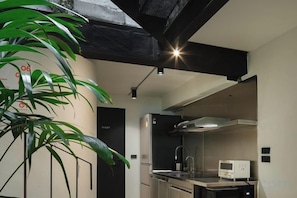 A modern kitchen with stainless steel appliances, a black countertop, and a visible microwave.