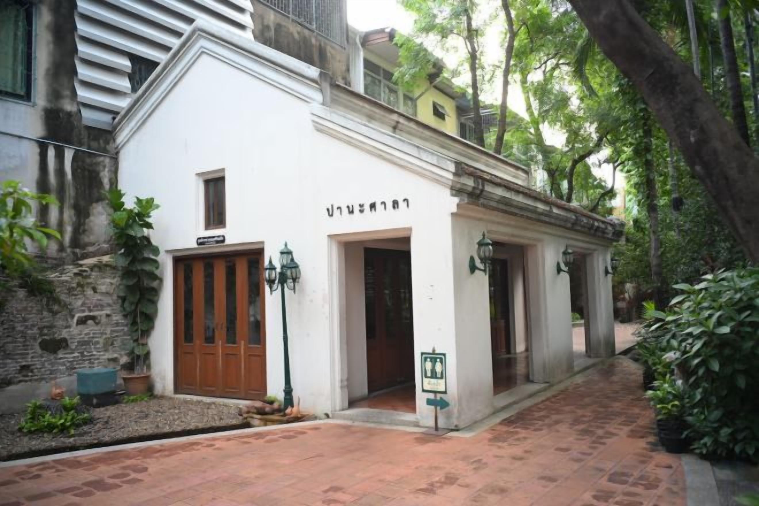 A white building with a wooden door and a sign above it.