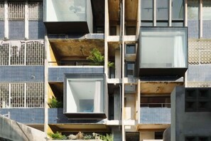 A building with multiple balconies, some with plants, and a mix of window styles.