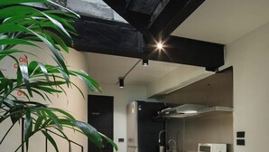 Una cocina moderna con electrodomésticos de acero inoxidable, una encimera negra y un inodoro a la vista.
