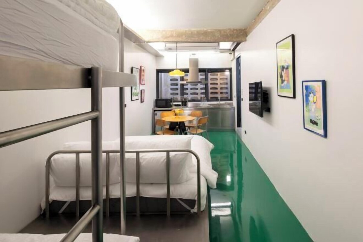 A narrow corridor with bunk beds, a kitchenette, and artwork on the walls.
