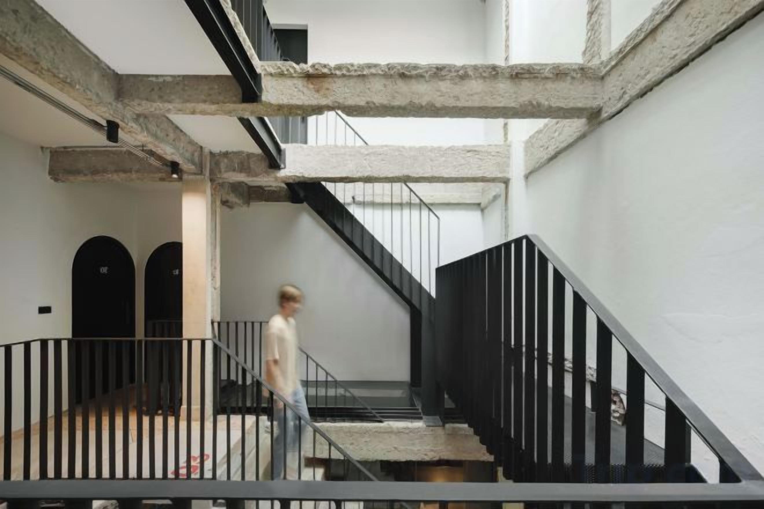 A staircase with black railings and a concrete floor, leading to an upper level.