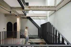 A staircase with black railings and a concrete floor, leading to an upper level. - Stupid Stay (Bangkok)