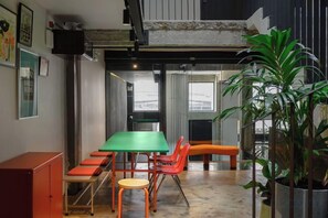 A conference room with a green table, orange chairs, and a potted plant.