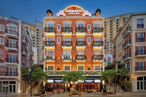 A multi-story hotel with a prominent sign, balconies, and a well-lit entrance.