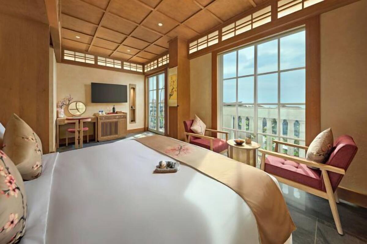 Ein Hotelzimmer mit einem großen Bett, einem Schreibtisch, einem Stuhl und Blick auf die Stadt.