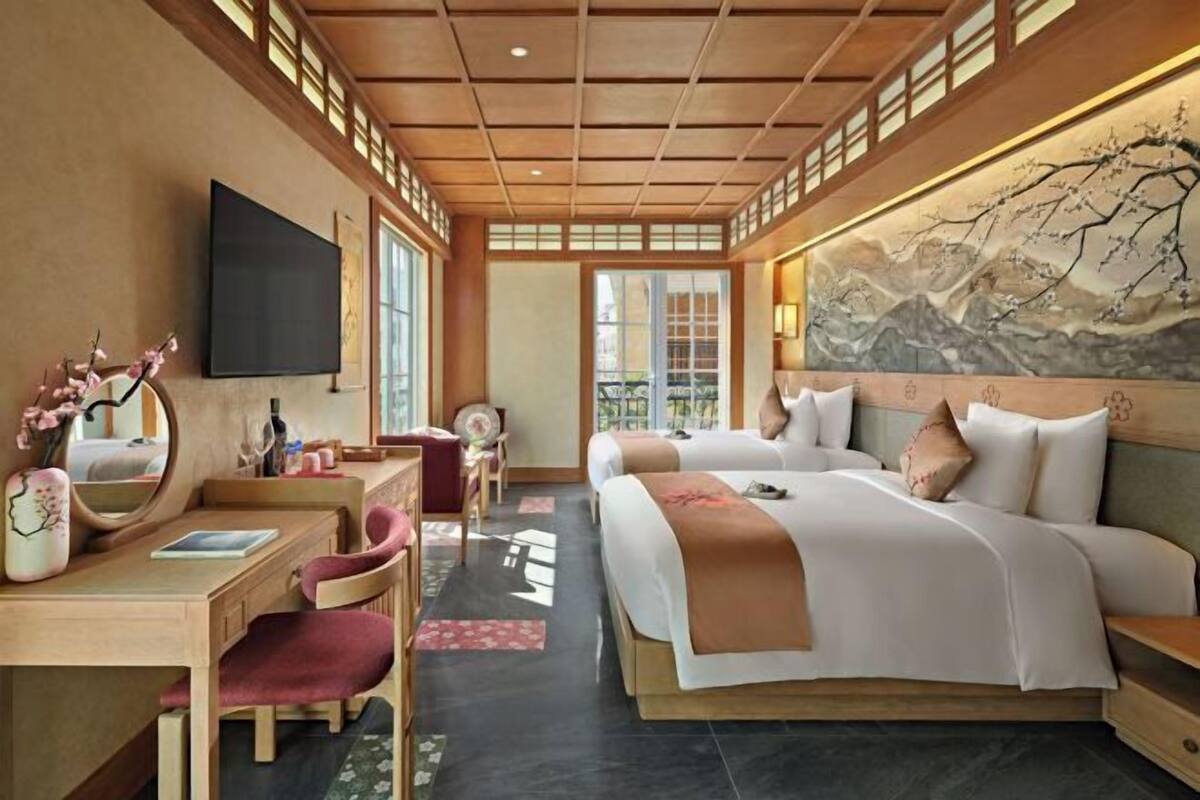 Ein Hotelzimmer mit einem großen Bett, einem Schreibtisch mit Stuhl, einem Fernseher und einem Bild an der Wand.