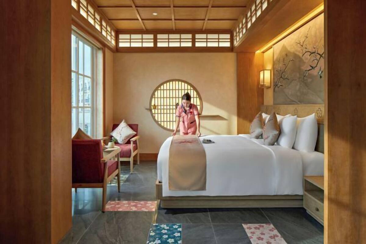 Ein Hotelzimmer mit Bett, Schreibtisch, Stuhl und einem großen Fenster.