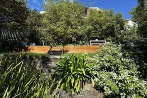 A garden with a pond, wooden steps, and various plants. - Nicolas Escape panoramic views luxury and space (Sandy Bay)