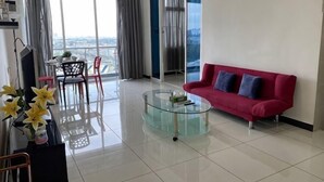 Un soggiorno moderno con un tavolino in vetro, un divano rosso e un balcone con vista.