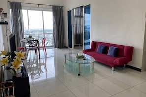 Ein modernes Wohnzimmer mit einem Glastisch, einem roten Sofa und einem Balkon mit Blick.