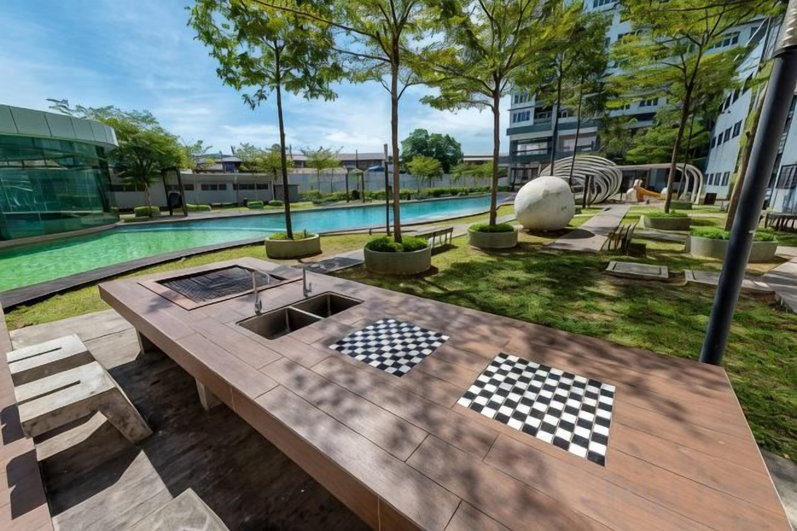 Zona piscina con una lunga panca, pavimento a scacchi e un edificio moderno sullo sfondo.