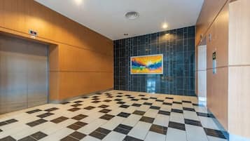 Un vestíbulo con piso a cuadros, una pintura en la pared y una puerta a la izquierda.