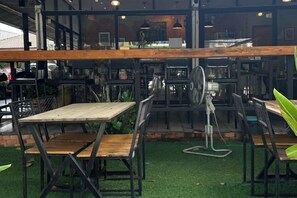 An indoor seating area with tables and chairs, a fan, and a grill. - Seven Seas Condo Resort OB D7 (Pattaya)