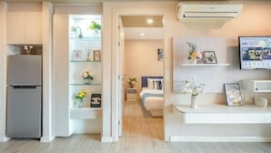 A modern kitchen with a built-in refrigerator, a dining area with a white table and chairs, and a living room with a sofa and a TV. - Seven Seas Condo Resort OB D7 (Pattaya)
