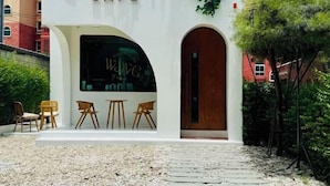 A cafe with a white exterior, a large arched window, and a wooden door. - Seven Seas Condo Resort OB D7 (Pattaya)