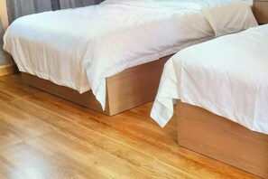 Ein Zimmer mit zwei Betten aus Holz, jeweils mit weißer Bettwäsche.