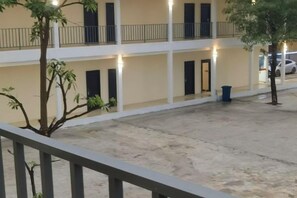 A multi-story building with balconies, a courtyard, and a tree. - Happy Hotel (Vientiane)