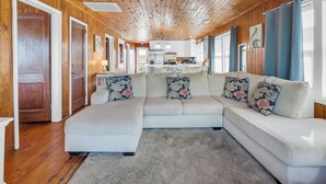 A cozy living room with a large sectional sofa, wooden ceiling, and a view to the kitchen. - Hot Tub-Waterfront 4BD Home-Cherry Grove-Pet Friendly-Sleeps 14 (North Myrtle Beach)