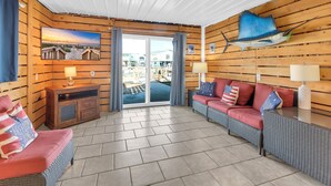 A cozy room with wooden walls, a large window, a sofa set, and a television. - Hot Tub-Waterfront 4BD Home-Cherry Grove-Pet Friendly-Sleeps 14 (North Myrtle Beach)