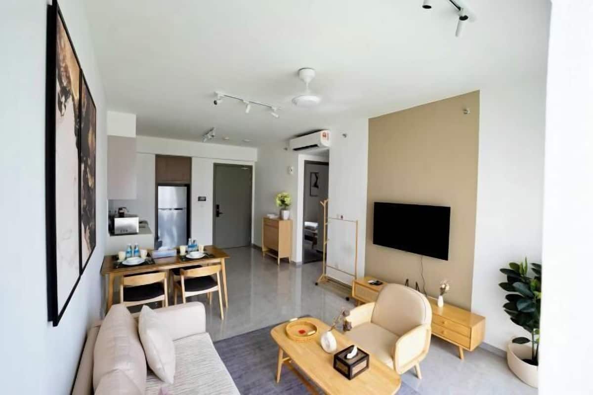 Een moderne woonkamer met een bank, salontafel, televisie en een eethoek met stoelen en een tafel.
