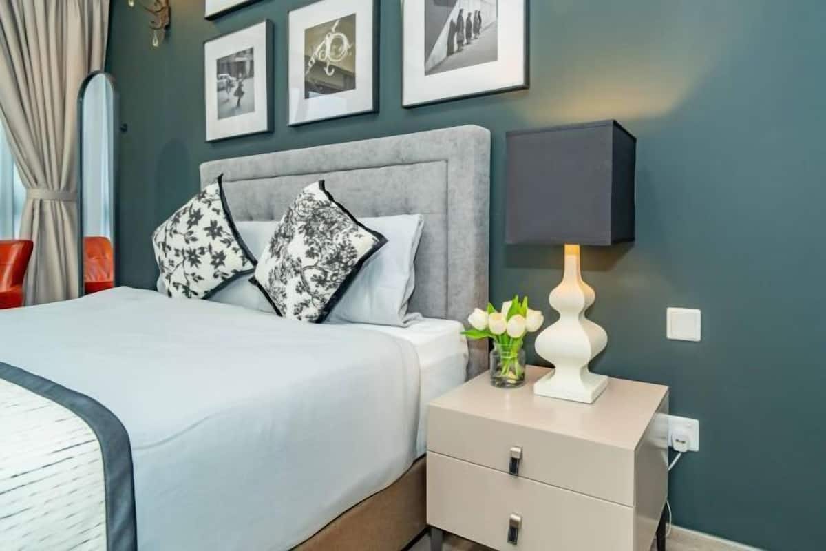 Een slaapkamer met een bed, nachtkastjes, een lamp en ingekaderde foto’s aan de muur.