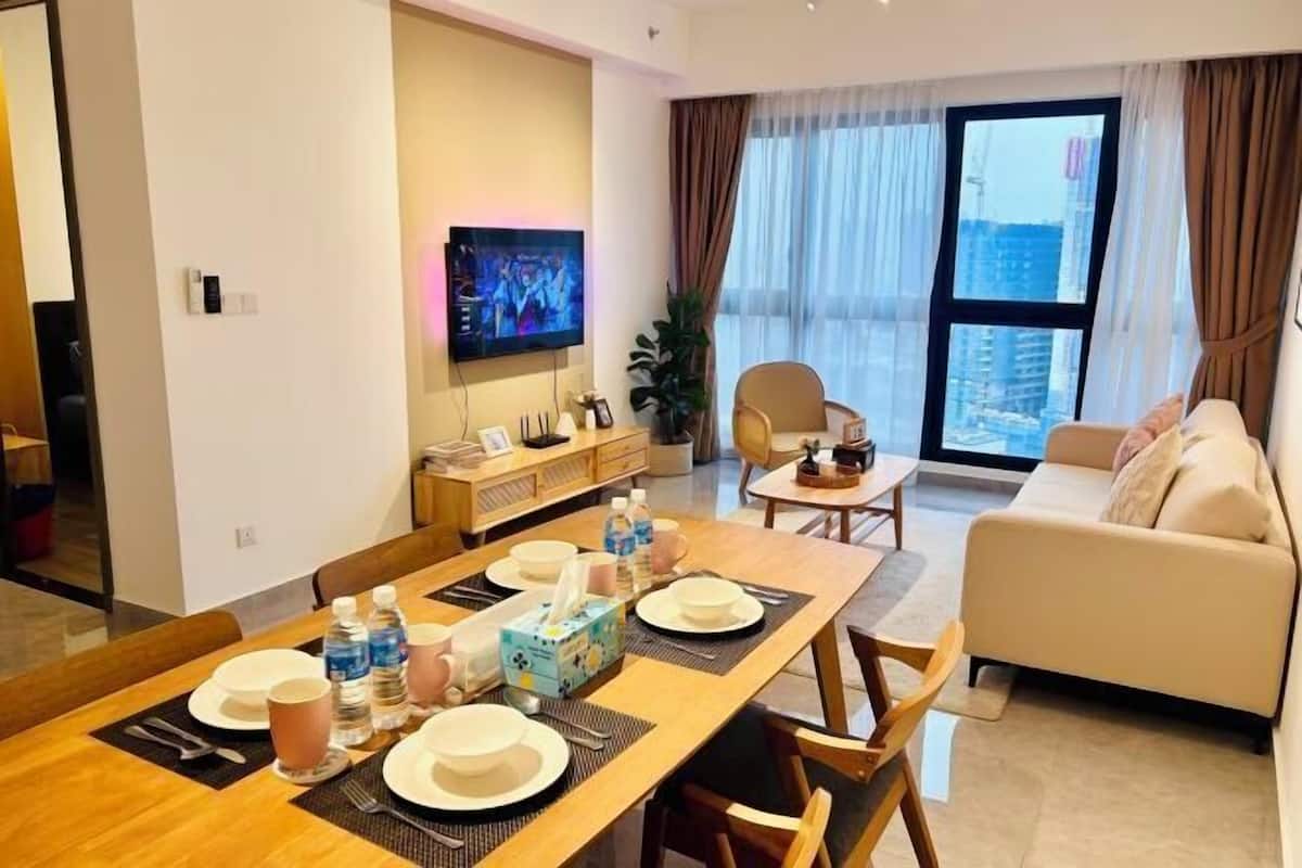 Een moderne woonkamer met een eethoek, een bank, een televisie en een groot raam met gordijnen.