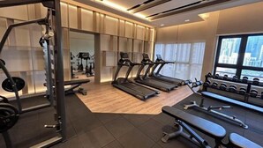 Een moderne sportschool met loopbanden, gewichtbanken en dumbbells.