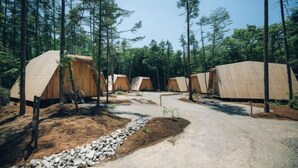 A row of wooden cabins in a forest setting with a gravel path leading through them. - SANU 2nd Home Kawaguchiko1st (Narusawa)