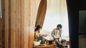 A room with a wooden slatted wall design, a bed with a white mattress, and a dog lying on the floor. - SANU 2nd Home Kawaguchiko1st (Narusawa)
