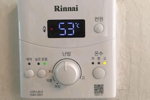En Rinnai vandvarmer med digitalt display, styreknopper og en QR-kode.
