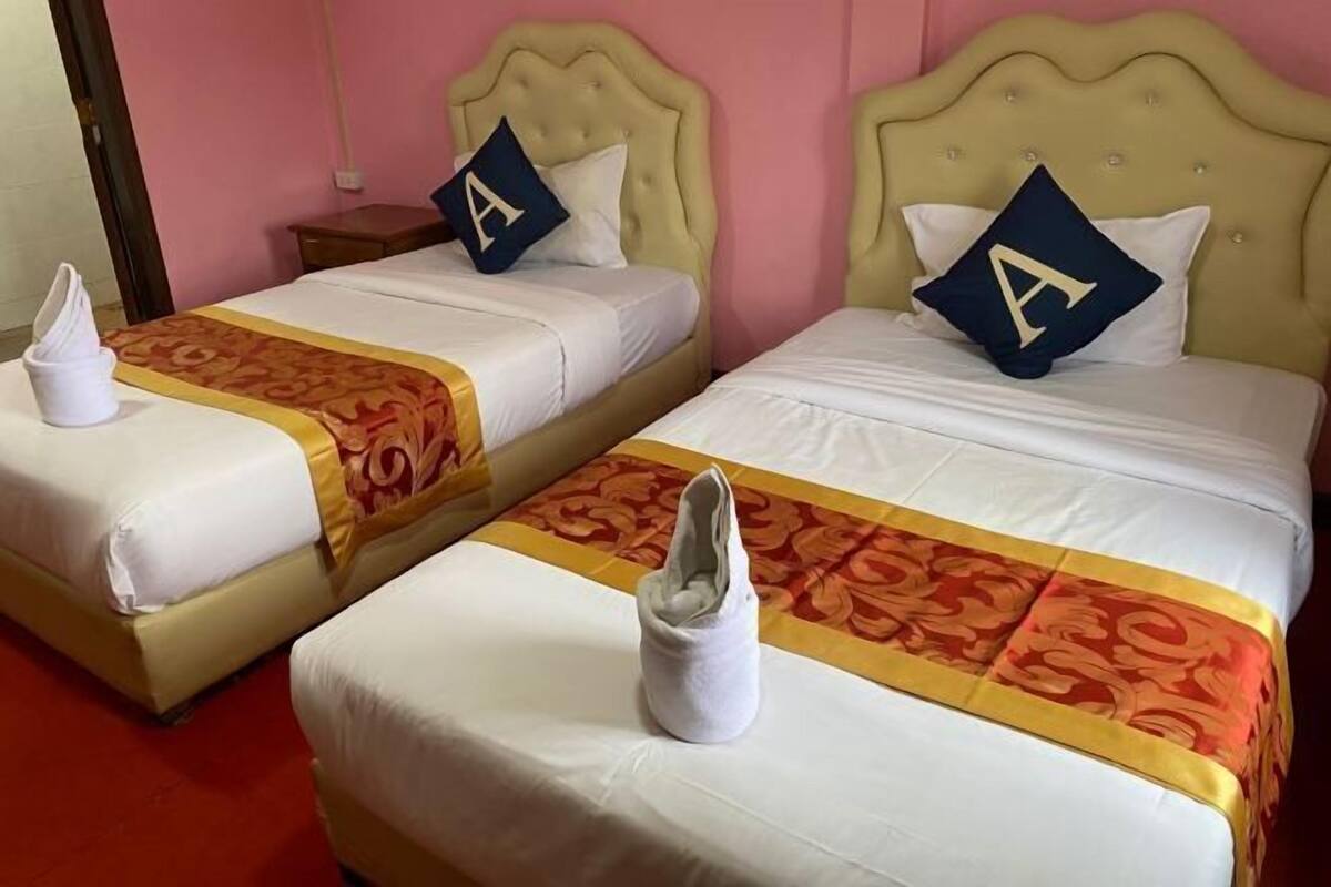 Two twin beds with matching headboards and pillows, each with a towel and a decorative bed runner.